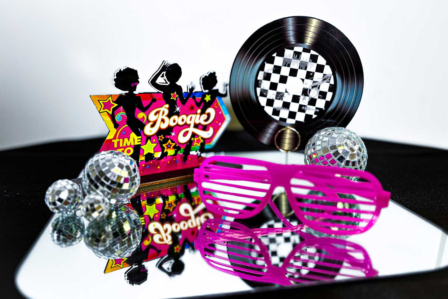 Centrepiece including disco balls, sunglasses, and a 'Boogie Time' sign on a reflective surface.