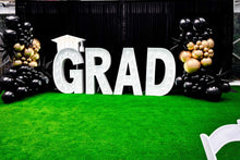 Load image into Gallery viewer, Graduation-themed decor with 'GRAD' letters and balloons on a green surface.