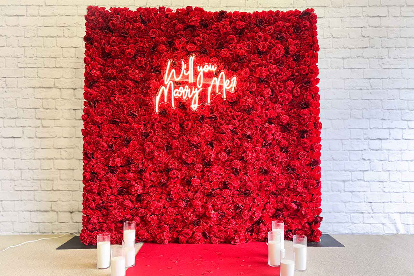 Red flower wall backdrop with “Will You Marry Me” neon sign for proposal and engagement events in Auckland NZ