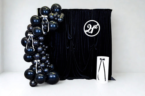 Black balloon arch with a black velvet backdrop 