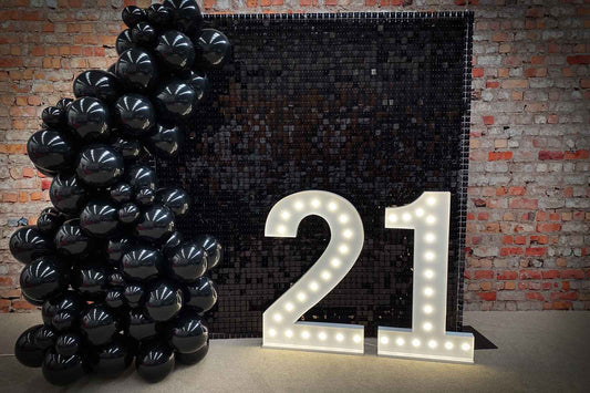 Elegant black 21st birthday event decor backdrop with balloon garland and modern party styling for a milestone celebration in Auckland NZ