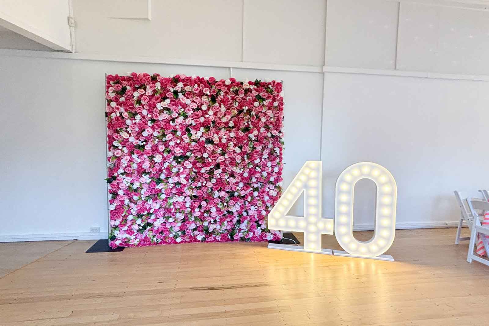 40 marquee lights in front of flower wall for event backdrop