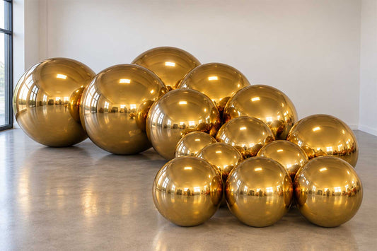 Giant gold inflatable balls hire in Auckland, styled as an event backdrop with balloon decor.