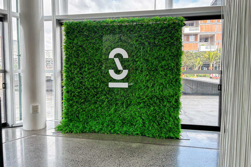 Green artificial grass wall with a logo in an indoor setting