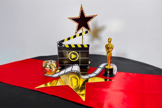 Movie-themed decorative set with Oscar statue, clapboard, and star on a red and black background
