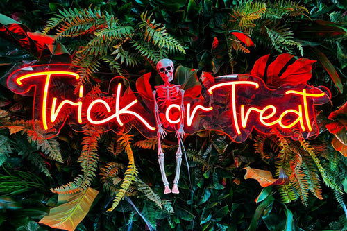 Neon 'Trick or Treat' sign with a skeleton surrounded by foliage