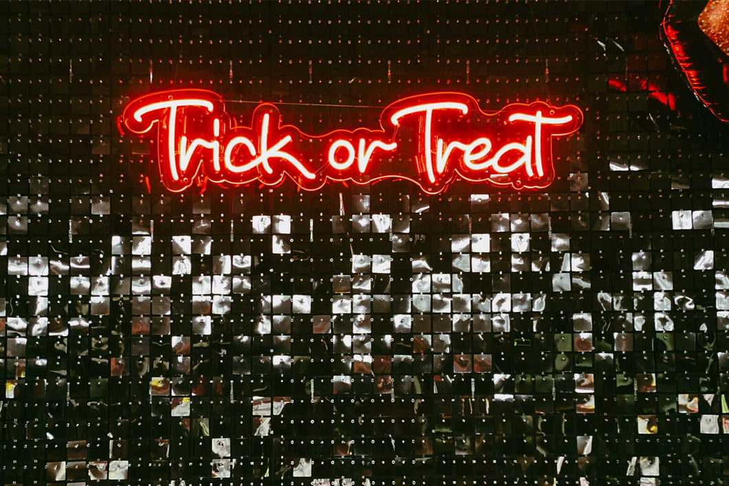 Neon 'Trick or Treat' sign on a dark background