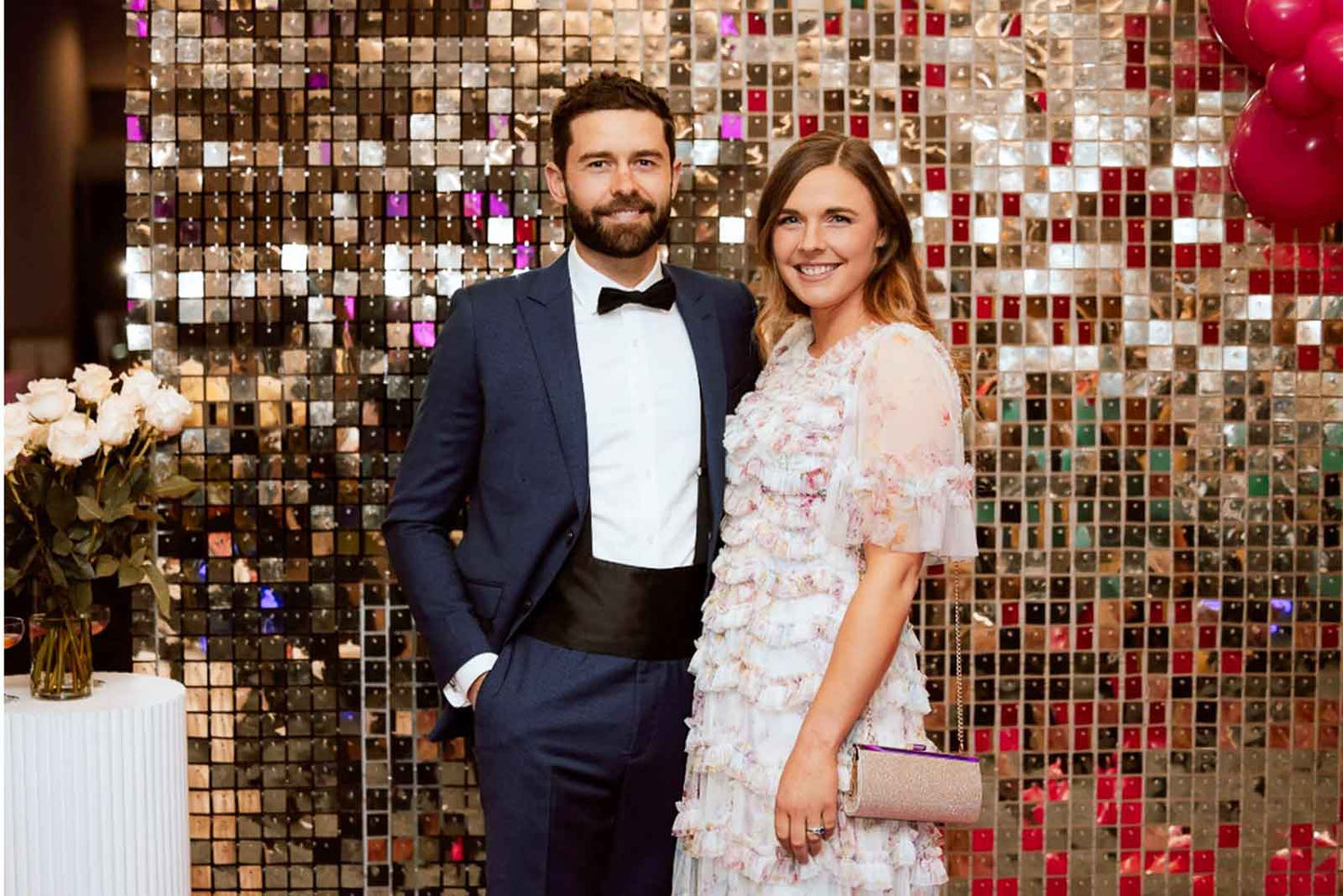 Corporate event in Auckland with attendees posing in front of a white and gold shimmer wall