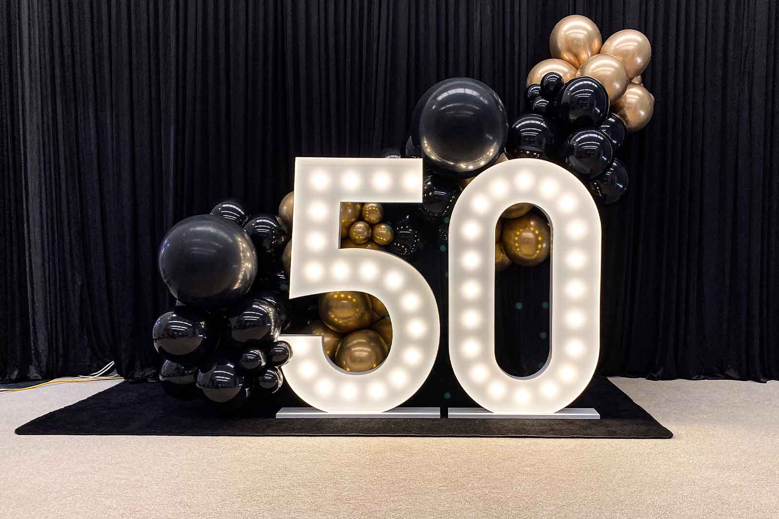 Black curtain backdrop with 50 marquee lights creating a striking and professional event display