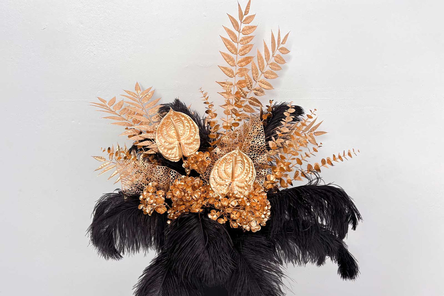 Elegant black feathers paired with gold florals creating a glamorous event backdrop for birthdays, galas, and Hollywood-style parties.