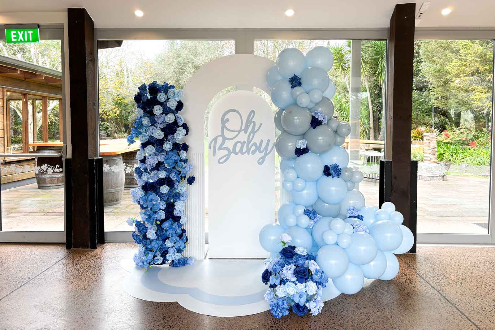 Blue "Oh Baby" baby shower backdrop with premium balloon garland, floral décor and personalised event styling for elegant celebrations in Auckland, NZ.
