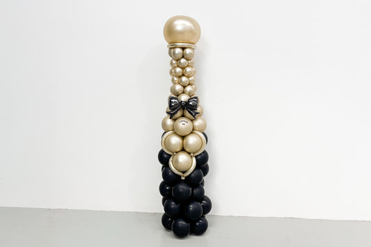 Large champagne bottle balloon tower display featuring gold, black, and metallic balloons, perfect for corporate events, celebrations, grand openings, and New Year's parties