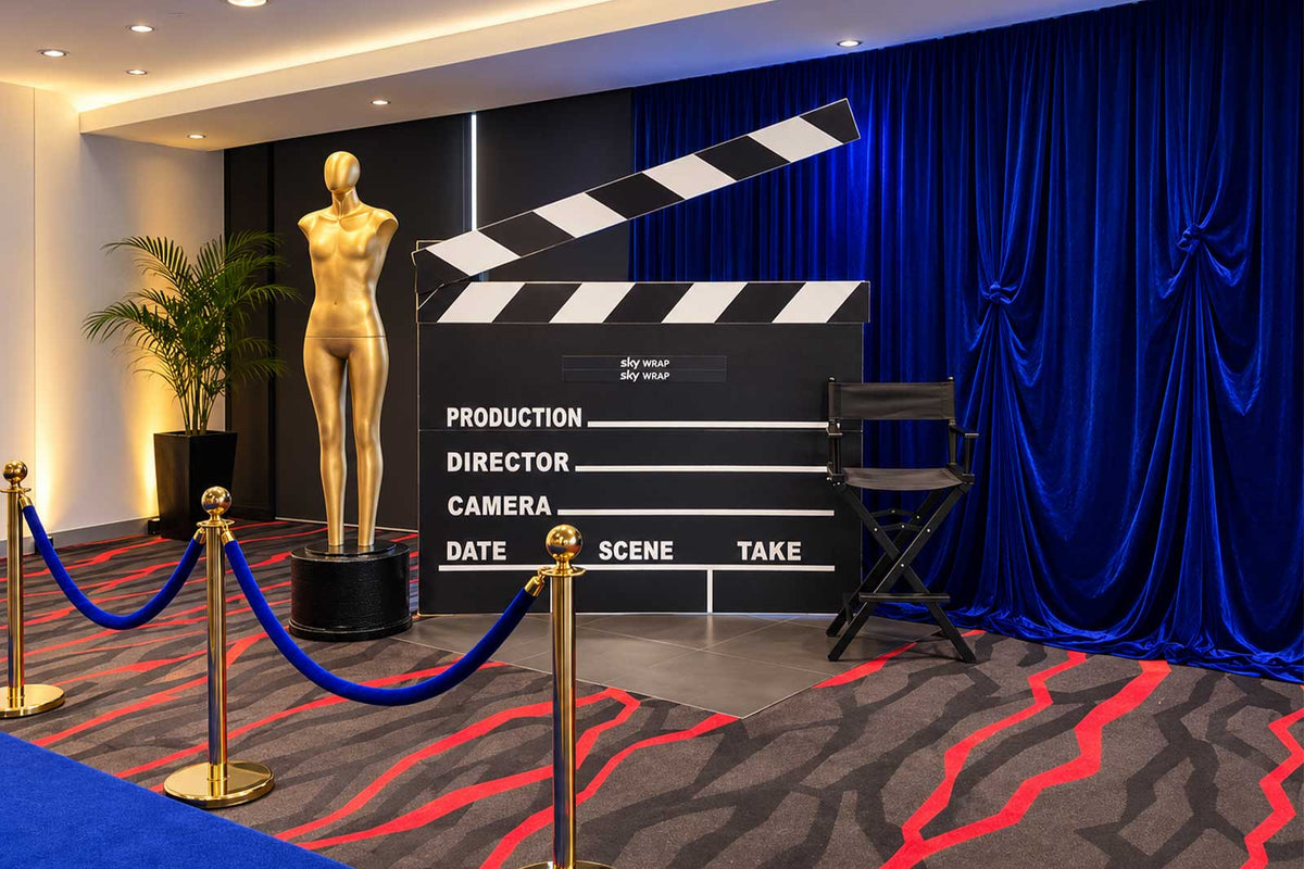 Clapper board with blue draping and director chair for movie-themed event styling
