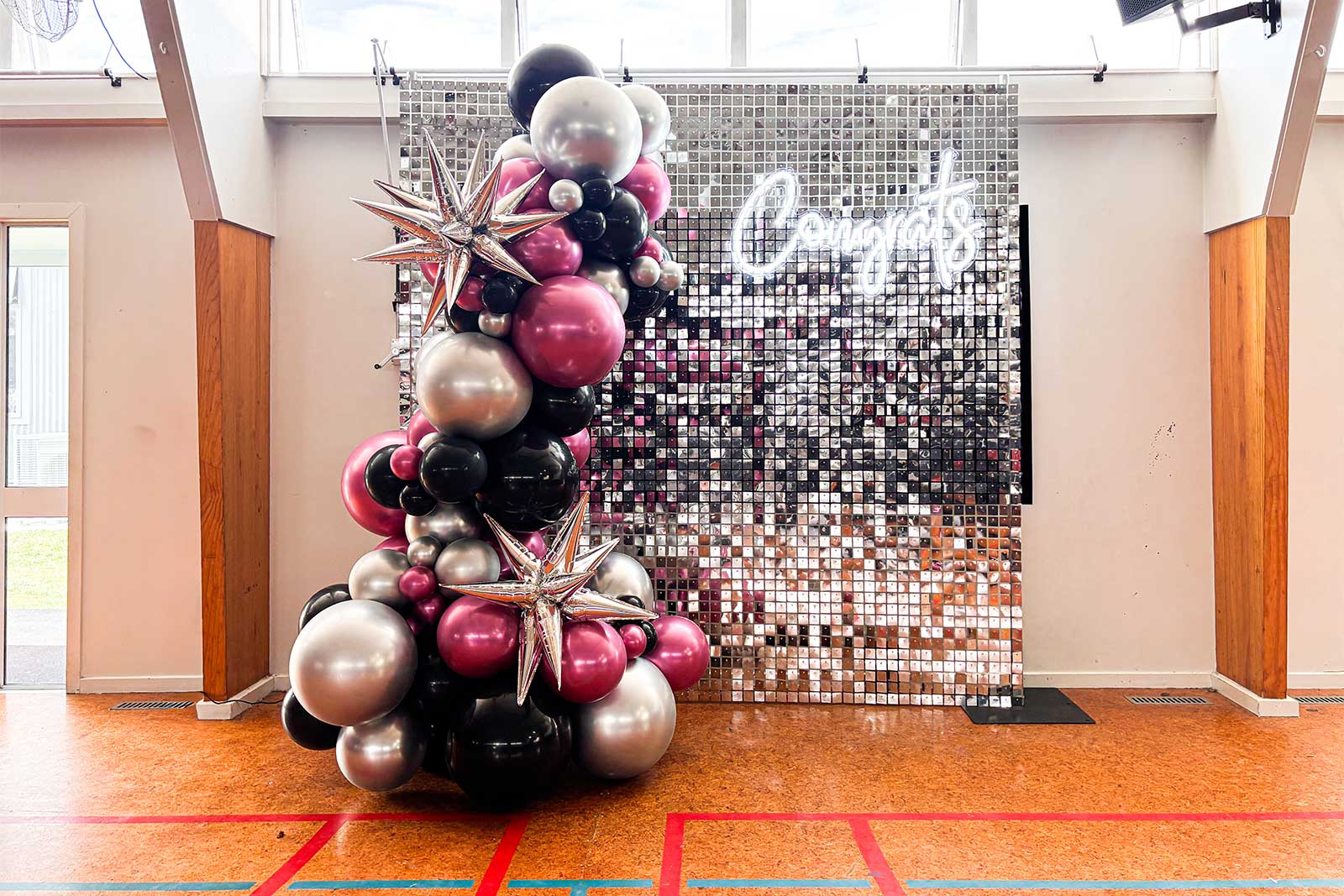 Congrats neon sign on silver shimmer wall with balloon garland