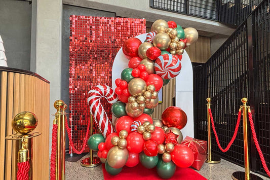 Corporate Christmas backdrop with festive balloon garland, custom signage and professional event styling for end-of-year functions in Auckland, NZ.