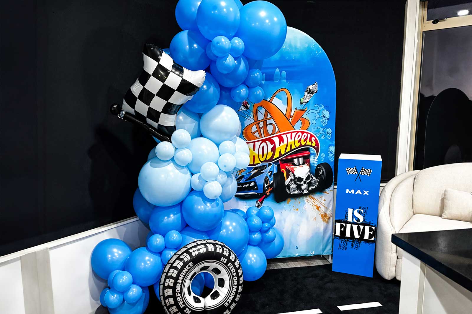 Themed kids party backdrop hire with colourful balloons and props and custom plinth