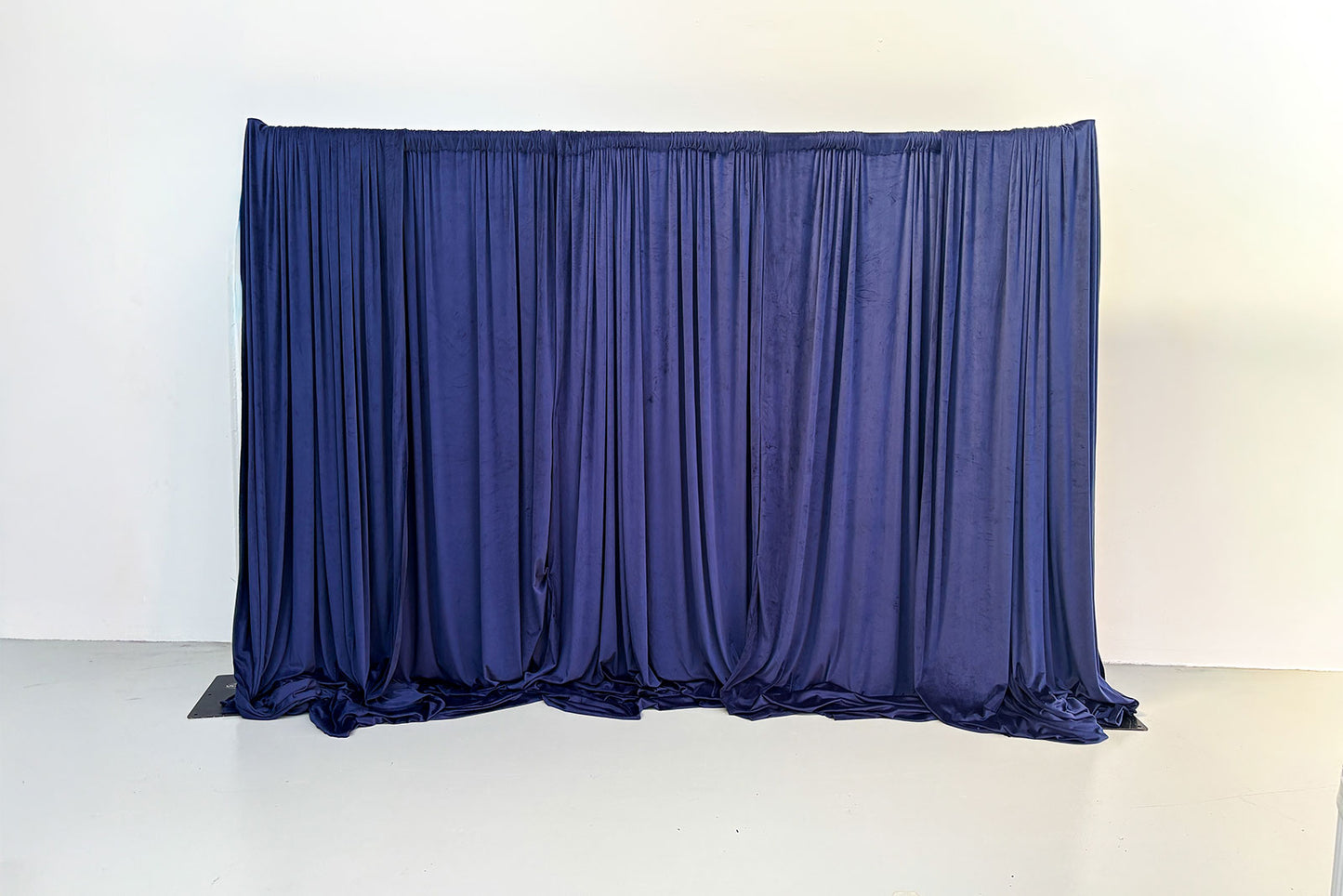 Luxury navy velvet curtain backdrop draping with elegant pleated fabric for weddings and events.