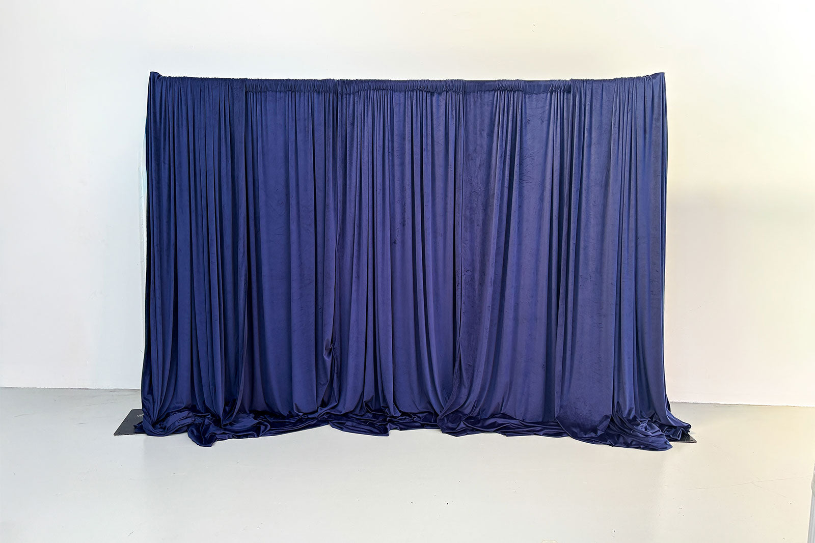 Luxury navy velvet curtain backdrop draping with elegant pleated fabric for weddings and events.
