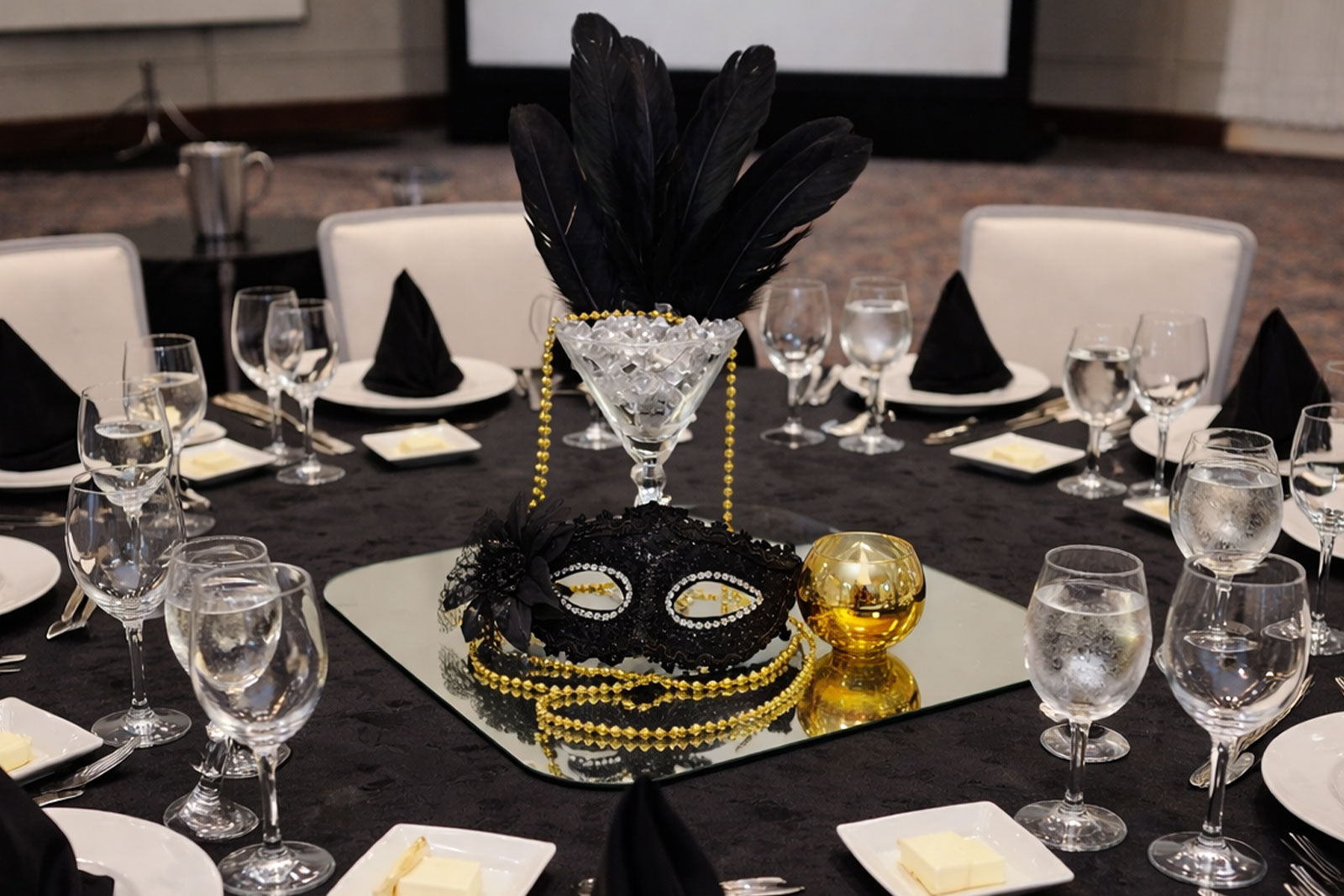 Masquerade ball centrepiece with gold and black styling, feathers and luxury table decor in Auckland