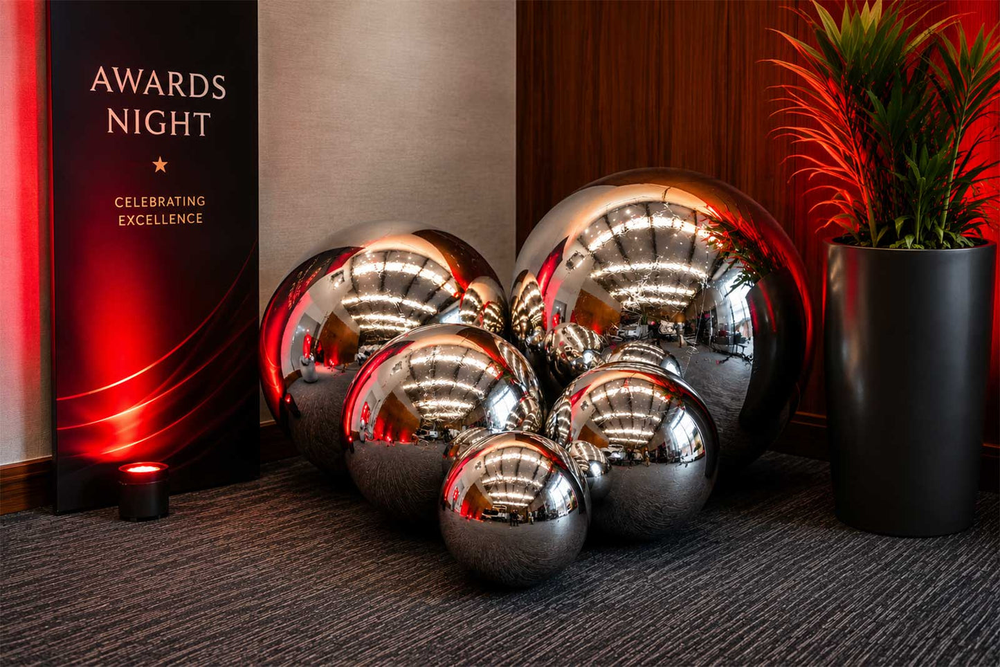 Oversized silver inflatable balls styled with an event backdrop for a modern and elegant party display