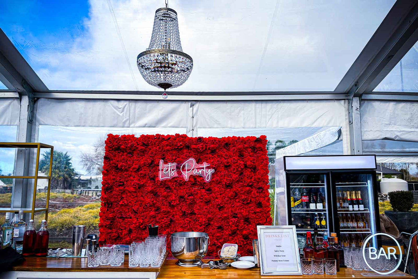 Red floral wall with “Let’s Party” neon sign for birthdays, team events, and social gatherings Auckland