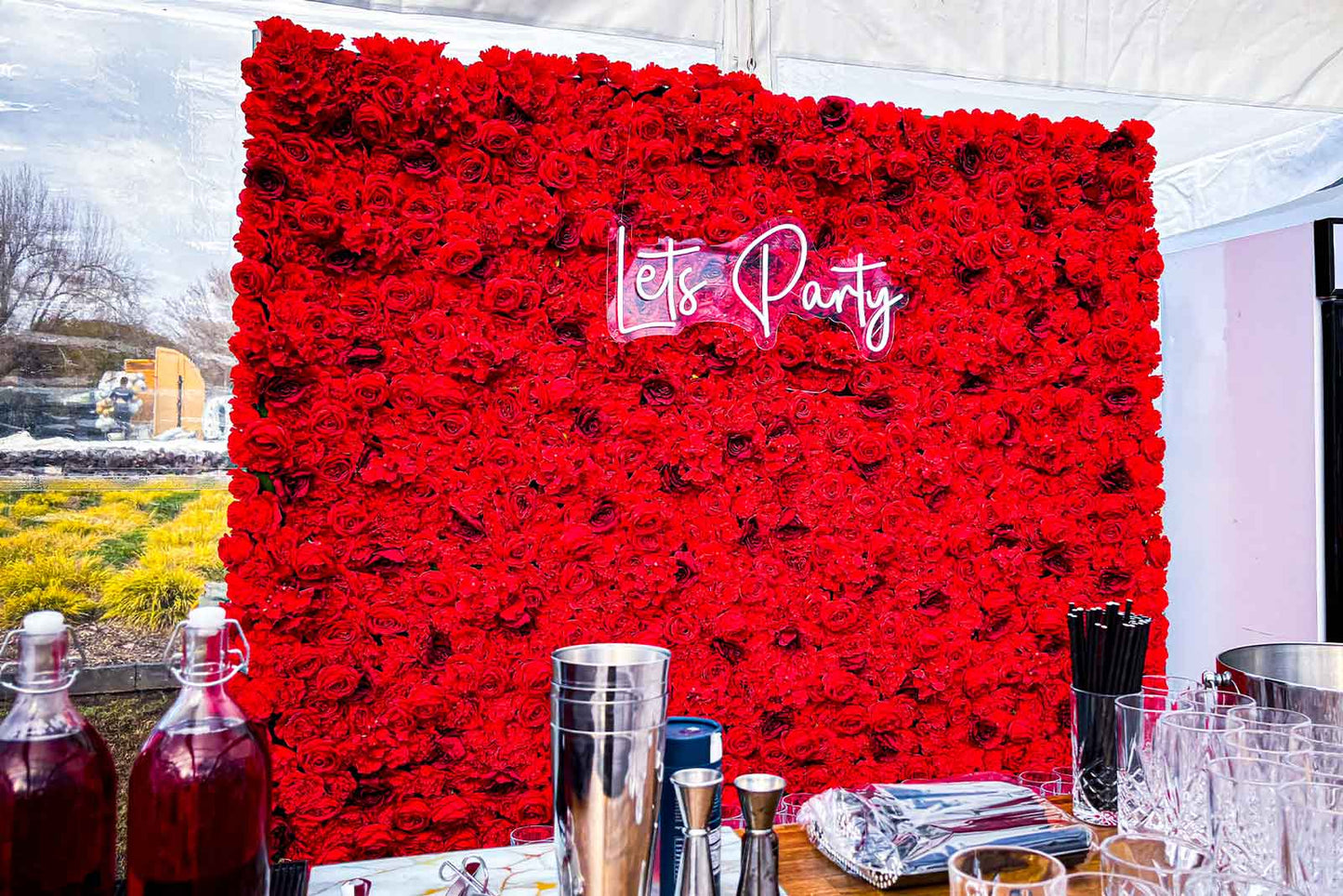 Red flower wall backdrop with “Let’s Party” neon sign for corporate celebrations and office parties in Auckland NZ