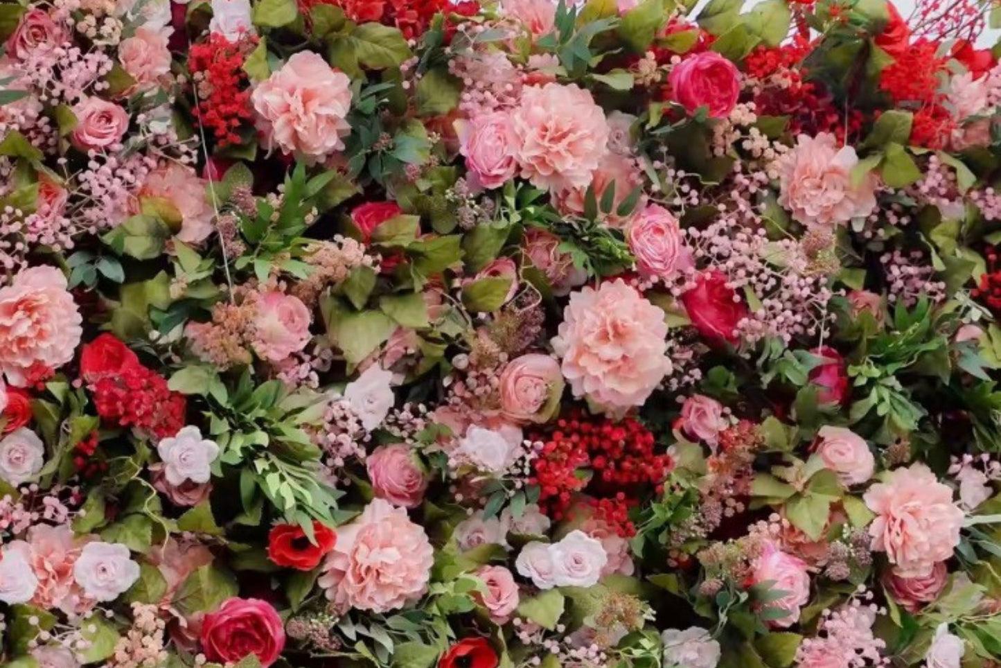 Red and pink flower wall creating a vibrant photo backdrop for events