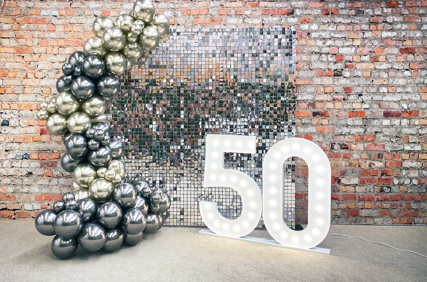 Silver shimmer wall backdrop featuring 50 marquee lights creating a glamorous photo area for events