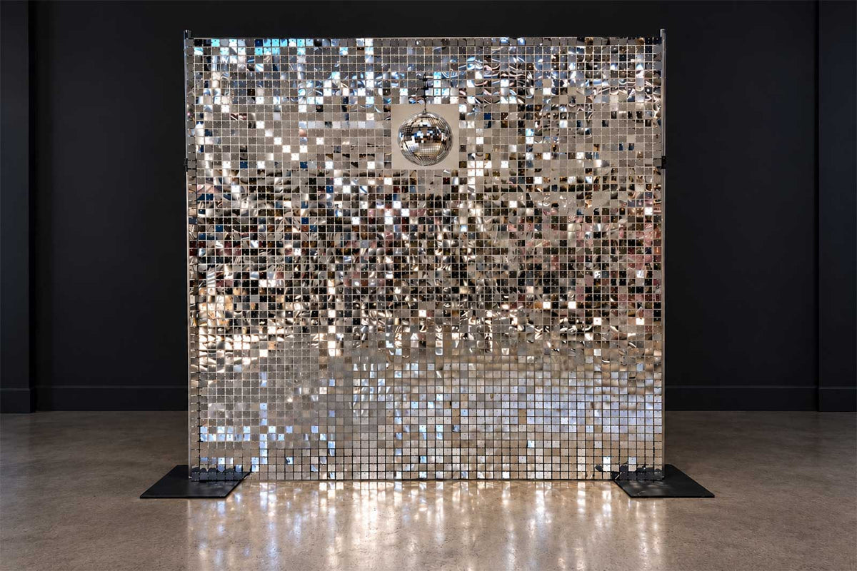 Silver shimmer wall backdrop with disco ball decorations for a disco-themed event