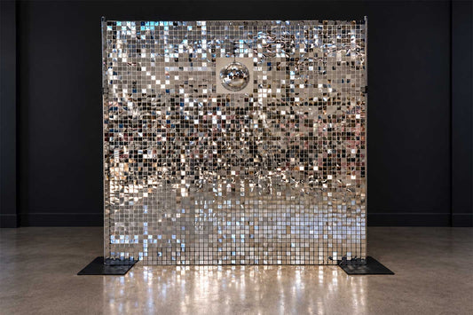 Silver shimmer wall backdrop with disco ball decorations for a disco-themed event