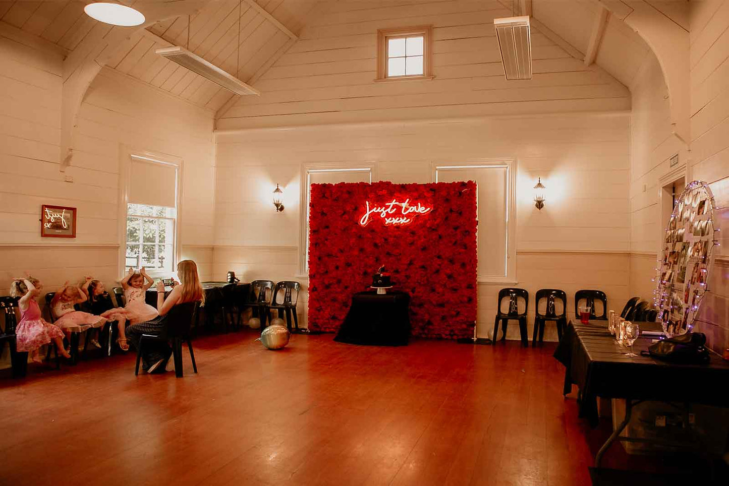 Red flower wall backdrop with “Just Love” neon sign for weddings, engagements, and romantic events in Auckland NZ