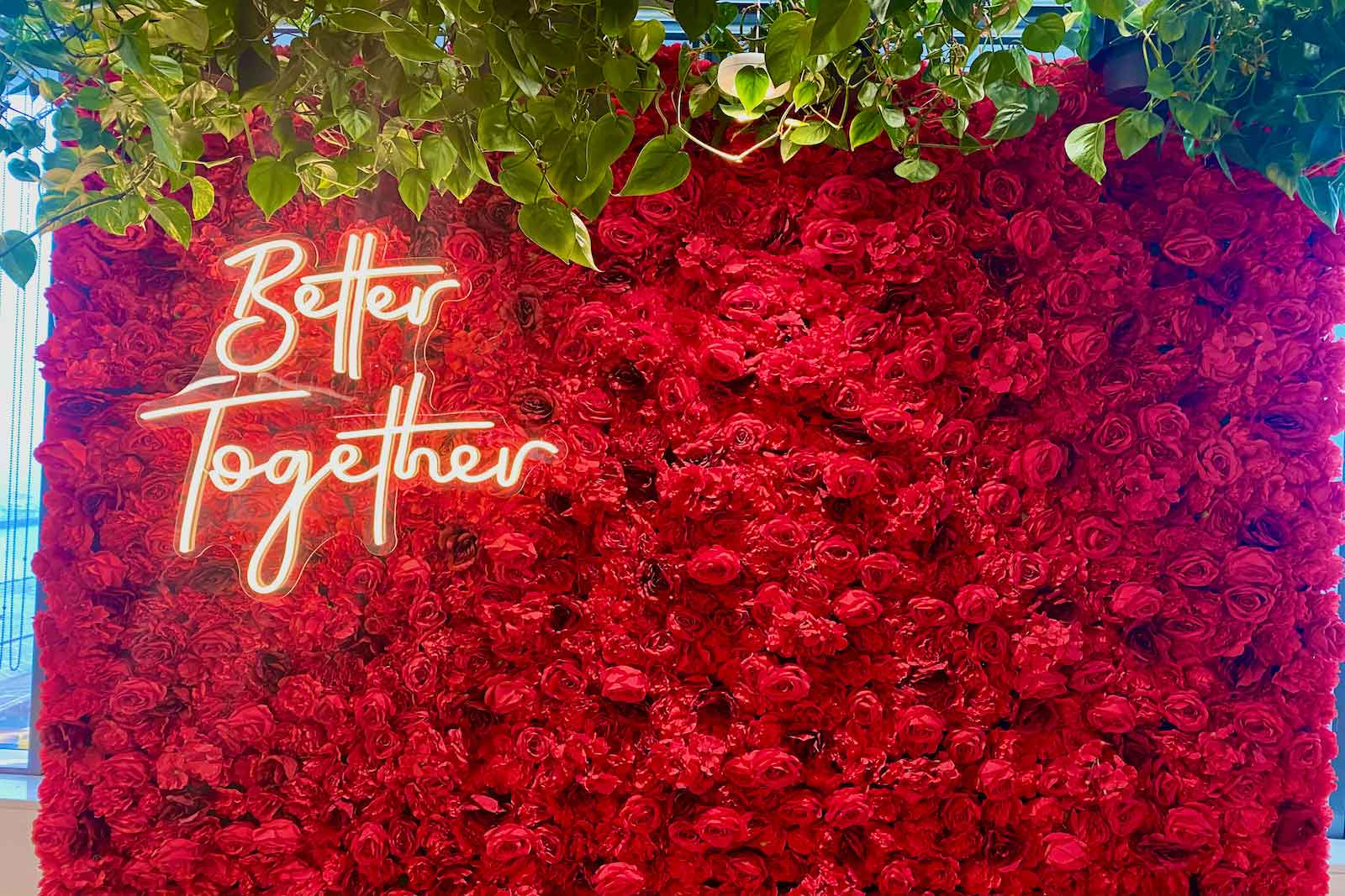 Red flower wall backdrop with “Better Together” neon sign for weddings, engagements, and romantic celebrations in Auckland NZ