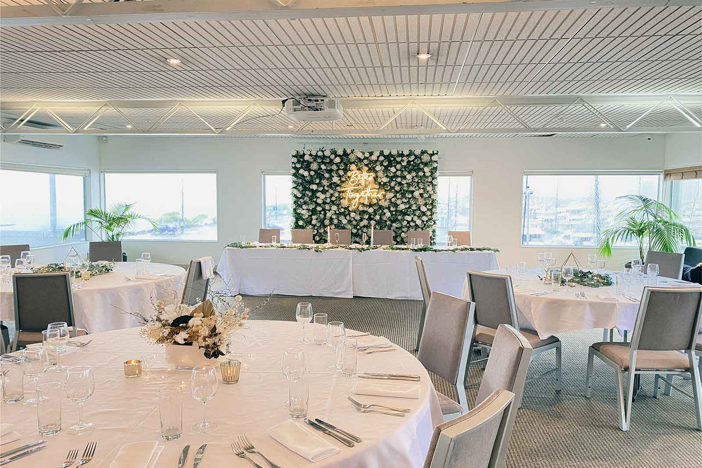 Wedding flower wall backdrop with "Better Together" neon sign for romantic photo moments